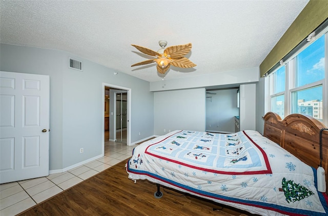 tiled bedroom featuring baseboards, a closet, visible vents, and a textured ceiling