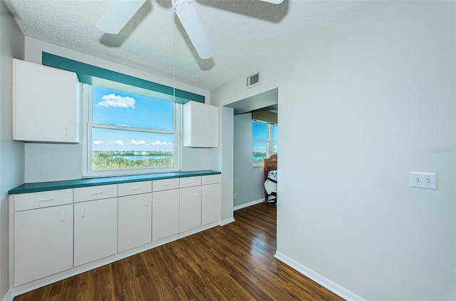 kitchen featuring visible vents, dark wood-style flooring, a textured ceiling, and white cabinetry