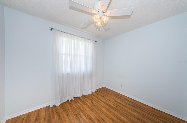 spare room with a textured ceiling, baseboards, and wood finished floors