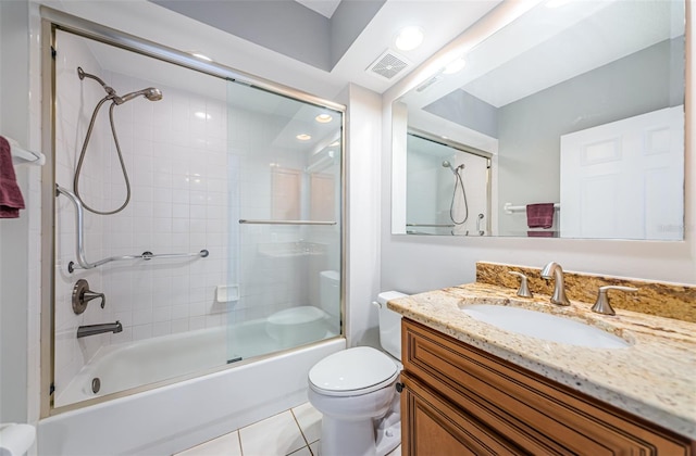 bathroom featuring toilet, vanity, visible vents, combined bath / shower with glass door, and tile patterned floors