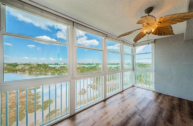 unfurnished sunroom featuring a water view and ceiling fan