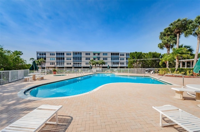 community pool with a patio area and fence