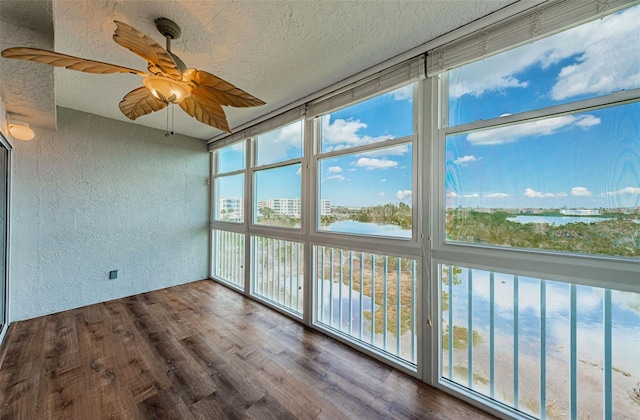 unfurnished sunroom featuring a ceiling fan and a water view