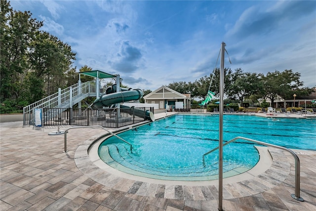 view of swimming pool with a patio area, a playground, and a water slide