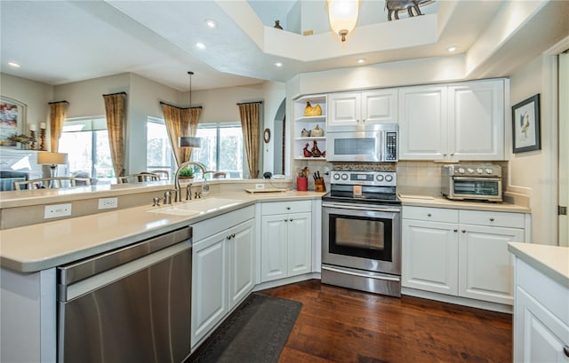 kitchen featuring sink, white cabinetry, hanging light fixtures, appliances with stainless steel finishes, and kitchen peninsula