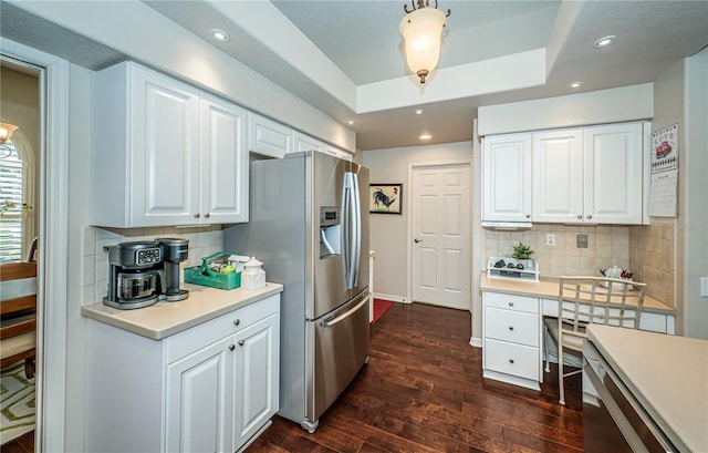 kitchen featuring stainless steel fridge with ice dispenser, white cabinets, decorative backsplash, a tray ceiling, and dark wood-type flooring