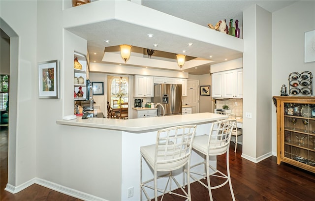 kitchen featuring white cabinets, a kitchen breakfast bar, kitchen peninsula, stainless steel refrigerator with ice dispenser, and dark wood-type flooring