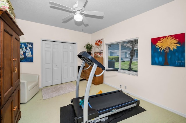 exercise room with a textured ceiling, light colored carpet, and ceiling fan