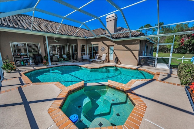 view of pool featuring a patio area, glass enclosure, ceiling fan, and an in ground hot tub