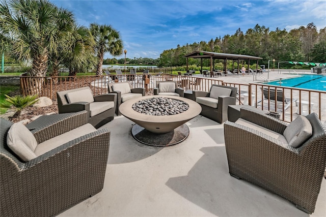 view of patio with a gazebo, a community pool, and an outdoor living space with a fire pit