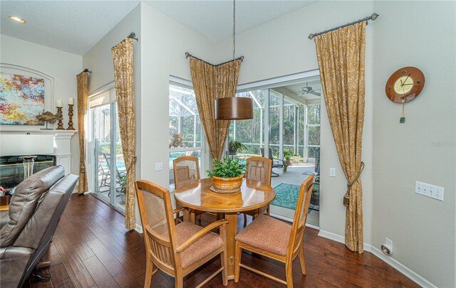 9101 Highland Ridge Way, Tampa, FL 33647 - dining area with hardwood / wood-style floors, ceiling fan, baseboards, and a glass covered fireplace