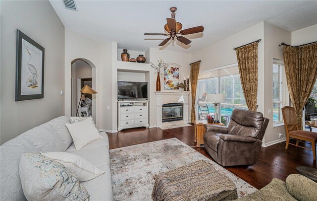 9101 Highland Ridge Way, Tampa, FL 33647 - living room featuring a ceiling fan, a fireplace with flush hearth, visible vents, arched walkways, and wood finished floors
