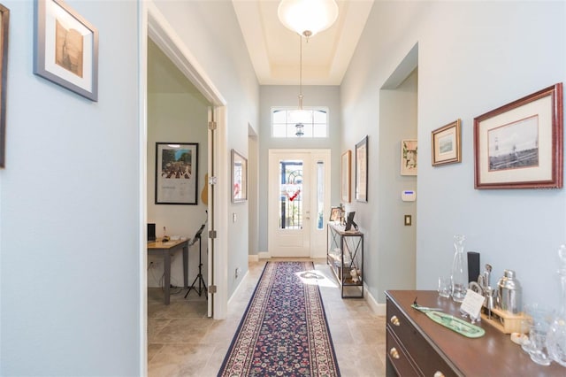 doorway with a tray ceiling and light tile patterned floors