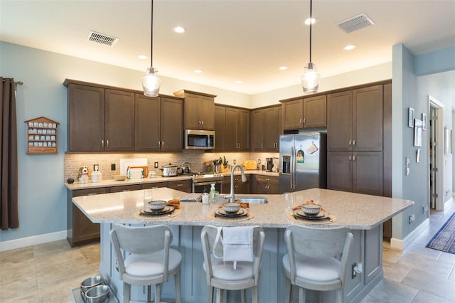 kitchen featuring decorative light fixtures, an island with sink, and appliances with stainless steel finishes