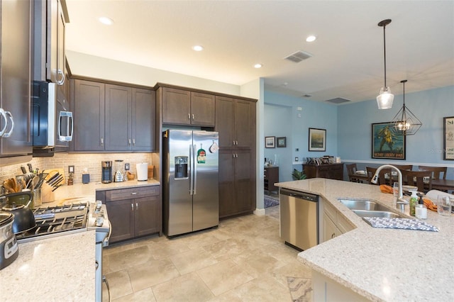 kitchen featuring appliances with stainless steel finishes, decorative light fixtures, light stone countertops, and dark brown cabinets