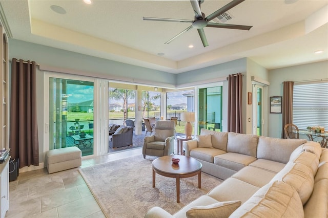 living room featuring ceiling fan and a tray ceiling