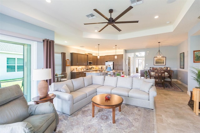 living room featuring a raised ceiling and ceiling fan