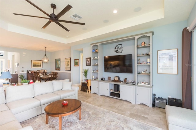 tiled living room featuring ceiling fan and a tray ceiling