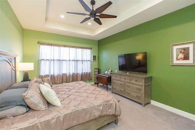 carpeted bedroom with ceiling fan and a tray ceiling