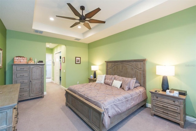 bedroom with light carpet, a tray ceiling, and ceiling fan