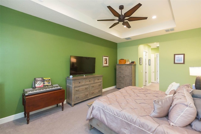 carpeted bedroom with a raised ceiling and ceiling fan