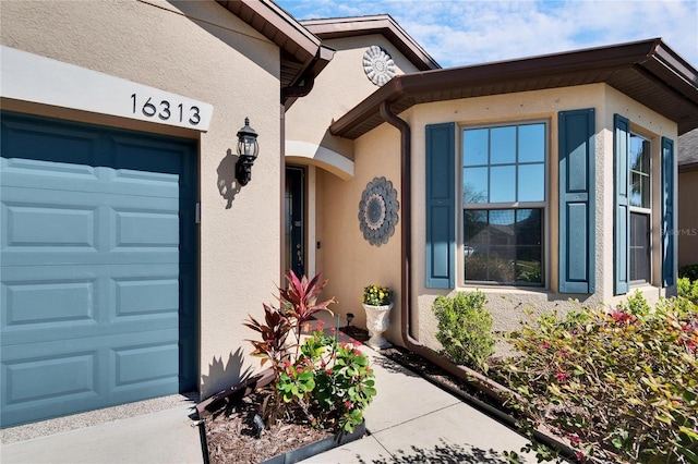 property entrance with a garage and stucco siding