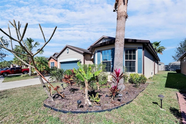 view of front of house with concrete driveway, a front lawn, an attached garage, and stucco siding