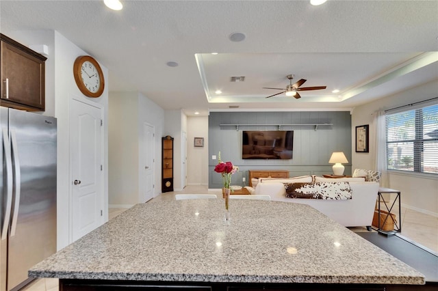 kitchen featuring visible vents, a kitchen island, a tray ceiling, and freestanding refrigerator