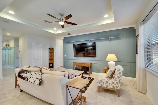 living area with a tray ceiling, visible vents, and light tile patterned floors