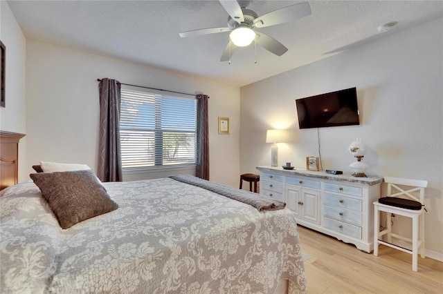 bedroom with light wood-style floors, a textured ceiling, and a ceiling fan