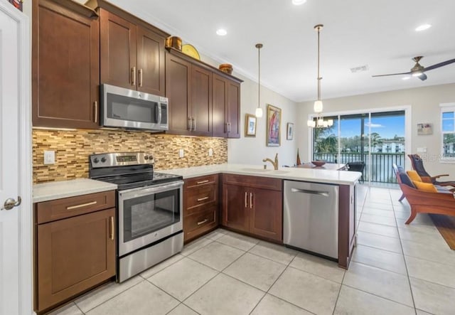 kitchen with a peninsula, light countertops, appliances with stainless steel finishes, tasteful backsplash, and decorative light fixtures