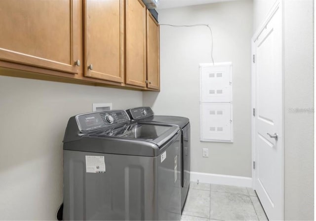 laundry room featuring light tile patterned floors, washing machine and clothes dryer, cabinet space, and baseboards