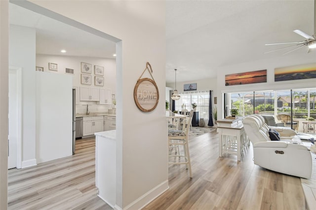 living room featuring sink, ceiling fan, and light wood-type flooring