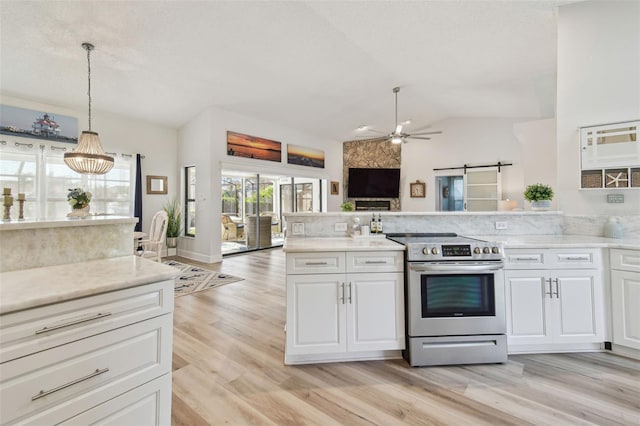 kitchen with pendant lighting, stainless steel electric range oven, a barn door, and white cabinets