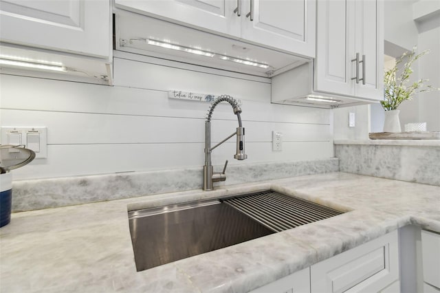 kitchen featuring white cabinetry, sink, and light stone counters