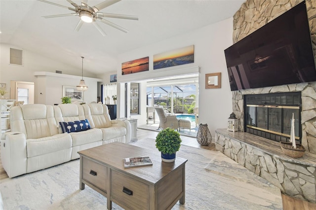 living room featuring vaulted ceiling, a stone fireplace, and ceiling fan