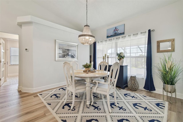 dining space featuring an inviting chandelier, wood-type flooring, and vaulted ceiling