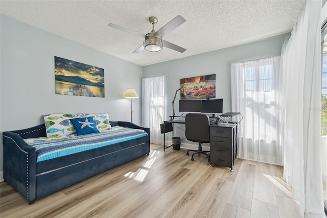 bedroom with ceiling fan, wood-type flooring, and a textured ceiling