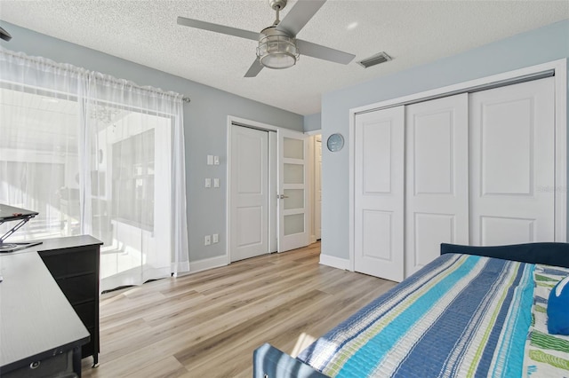 bedroom with a closet, ceiling fan, light hardwood / wood-style floors, and a textured ceiling