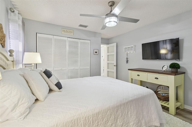 bedroom with ceiling fan, a closet, hardwood / wood-style floors, and a textured ceiling