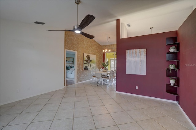 tiled empty room with high vaulted ceiling and ceiling fan with notable chandelier