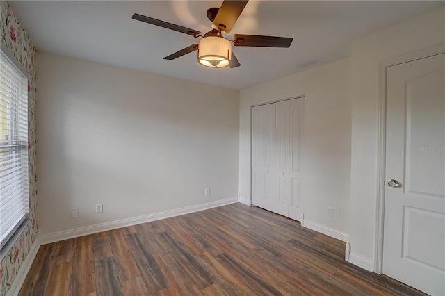 unfurnished bedroom featuring dark wood-type flooring, ceiling fan, and a closet