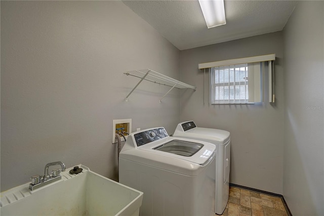 laundry room with separate washer and dryer, sink, and a textured ceiling