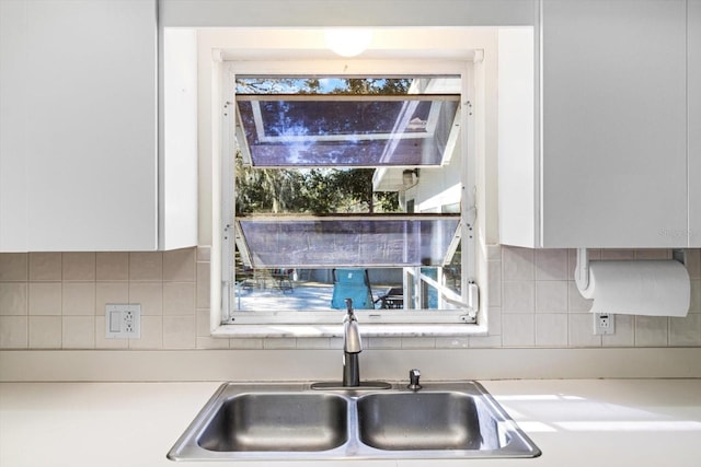 kitchen with tasteful backsplash, sink, and white cabinets