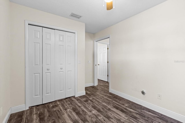 unfurnished bedroom with dark wood-type flooring, a closet, and ceiling fan