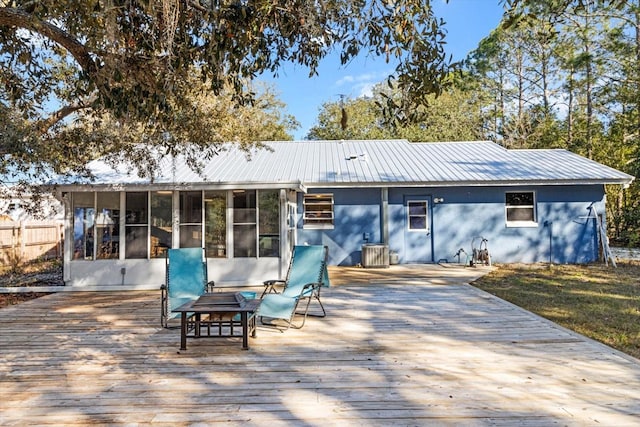 rear view of house with central AC unit, a fire pit, a sunroom, and a deck