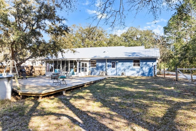 back of house featuring a wooden deck, a sunroom, and a yard