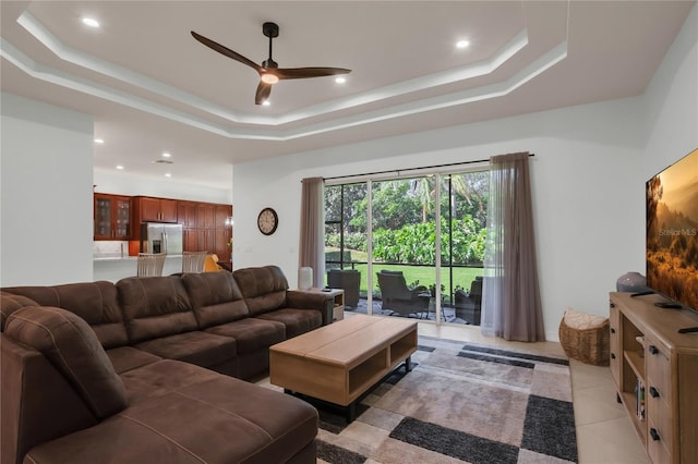 tiled living room featuring ceiling fan and a raised ceiling