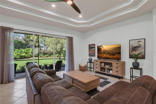 living room featuring light tile patterned floors, a tray ceiling, and ceiling fan