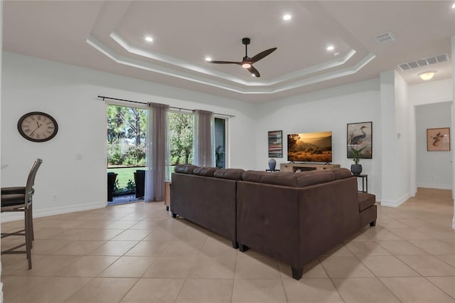 living room with light tile patterned floors, a raised ceiling, and ceiling fan